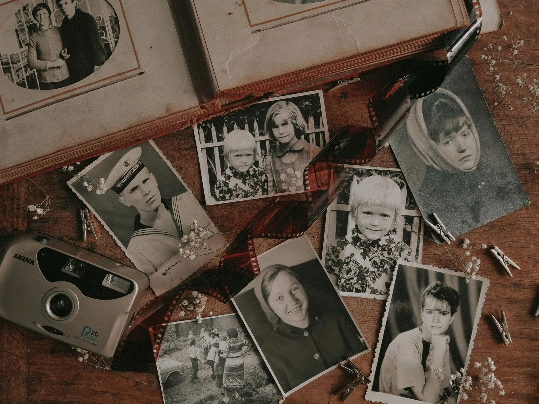 A spread of black and white family portrait prints and a curl of film negatives on a wooden table