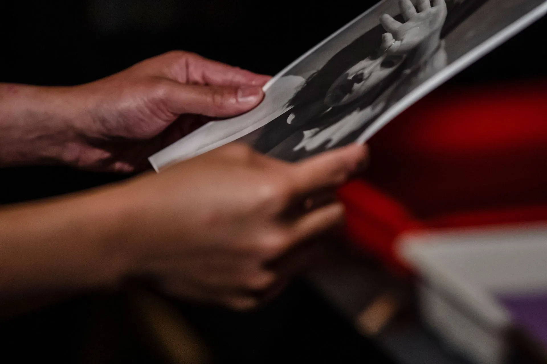 Two hands holding an old black and white photograph that is visibly curled along its length