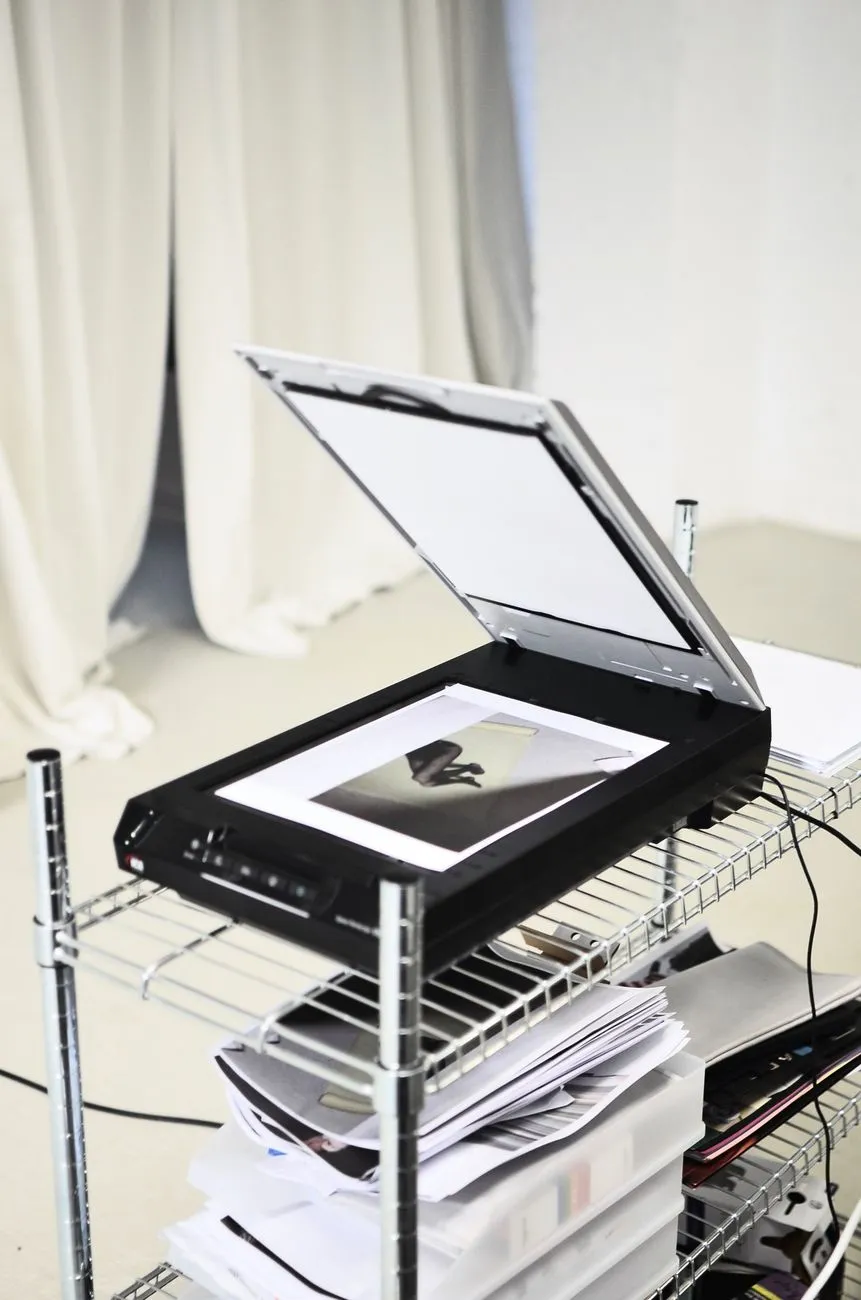 An open flatbed scanner mid-scan with a small photograph placed on the glass at home
