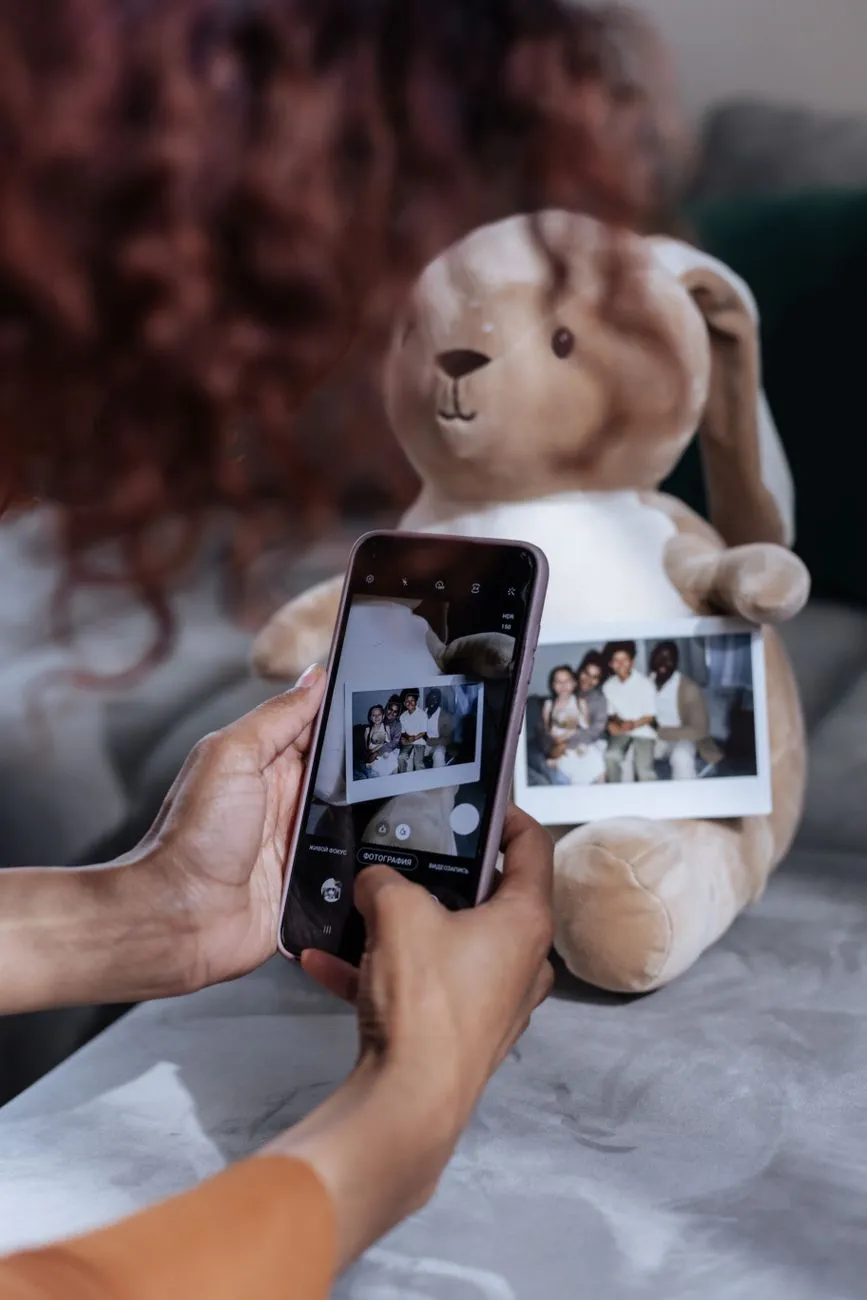A hand holding a smartphone, its camera app framing an old family photograph for capture